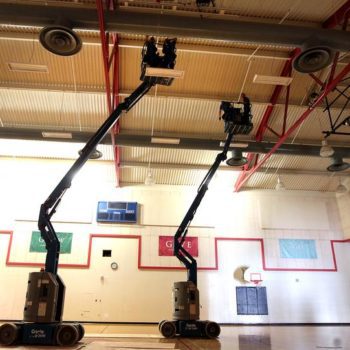 Inside a school gym with work being done on energy saving lights