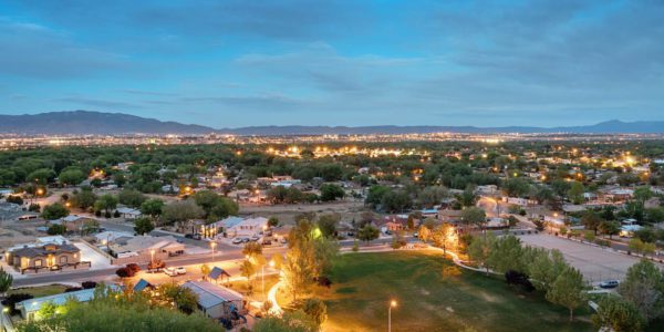 Suburb of Albuquerque New Mexico at dusk, with lighted park in the middle of houses against a blue sky turning dark.